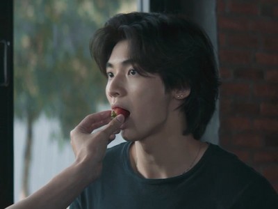 In puts a strawberry in Wang's mouth.
