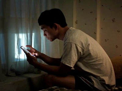 Cheol Jun looks at his phone in his bedroom.