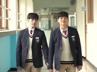 Hyun Woo and Ji Seok walk in the school hallway together.