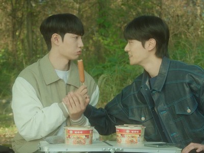 Min Jun and Jin Hwan eat a sausage.