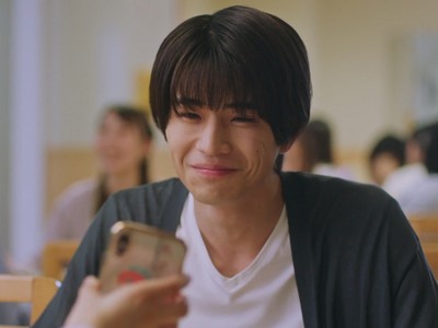 Kohei and Maya communicate on their phones in the cafeteria.