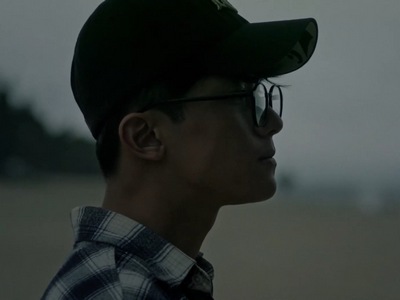 An adult Sangbeom stares wistfully at the sea.