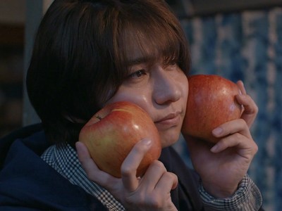 Azuma puts apples beside his cheeks.
