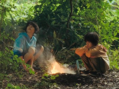 Yori and Minato sit around a fire.