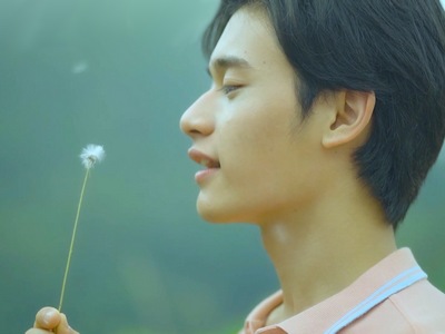 Mork blows on a dandelion flower.