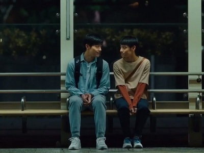 Jie and Hui sit at a bus stop together.