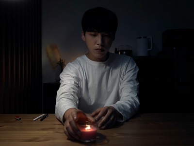 Ha-jun lights a candle in his dark apartment.