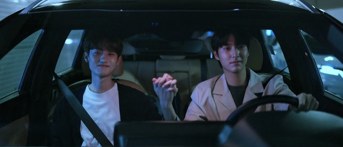 Jae Won and Ji Hyun drive in a car together, holding hands.