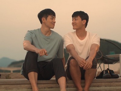 Seung Hyun and Jong Chan sit by the pool, smiling at each other.